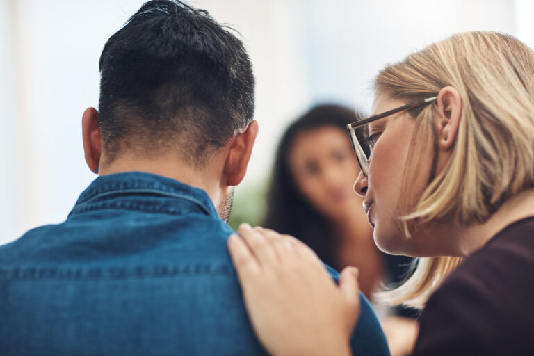 funeral etiquette with person at a funeral being consoled by others, hand on shoulder